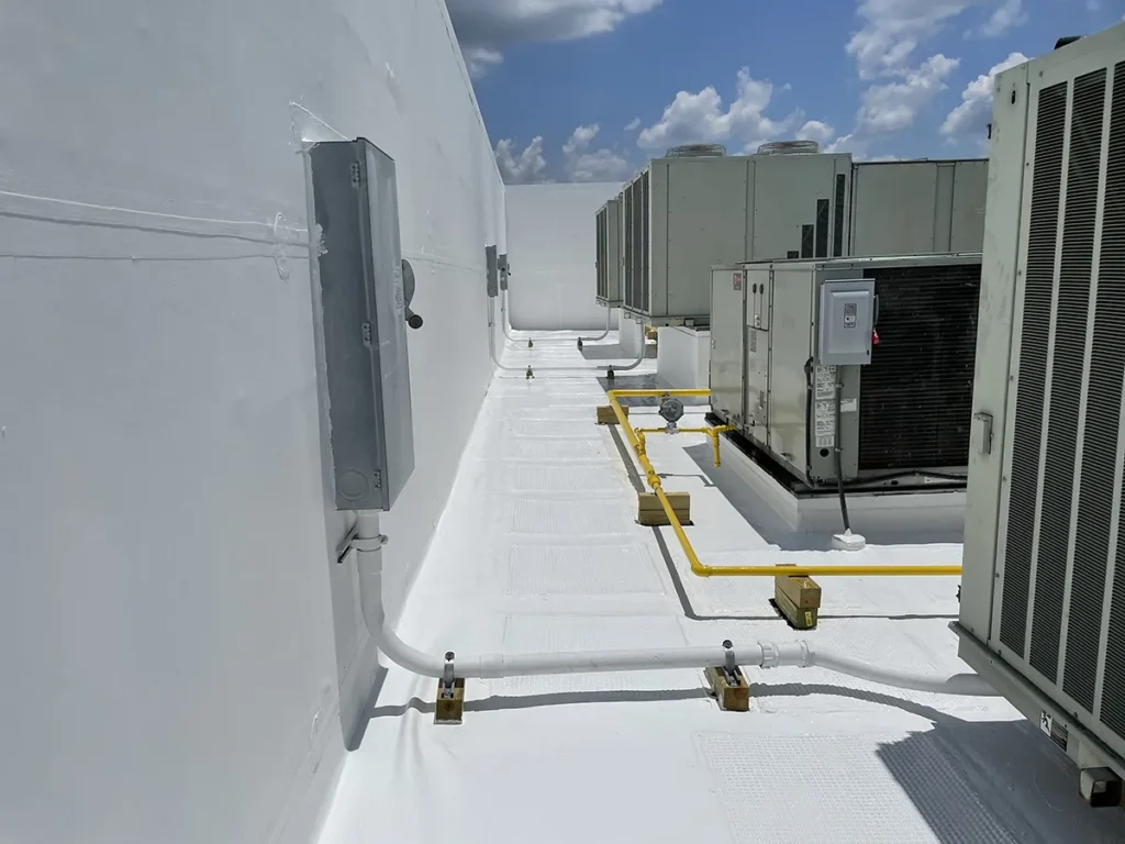 Image showing where roof, parapet wall, and AC units meet that have been treated with high-solids silicone roof coating.