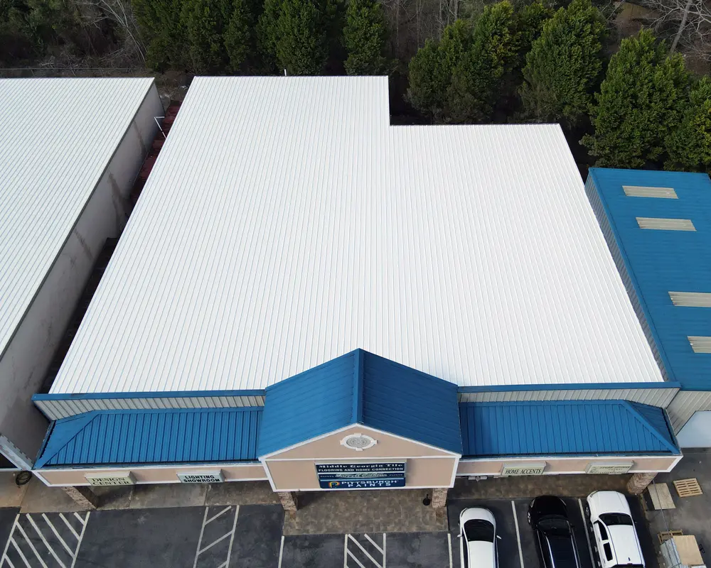 Aerial view of a large metal roof's top coat application (Acrylic 211), showcasing the uniform coverage and reflective properties of the Met-A-Gard roof coating system.