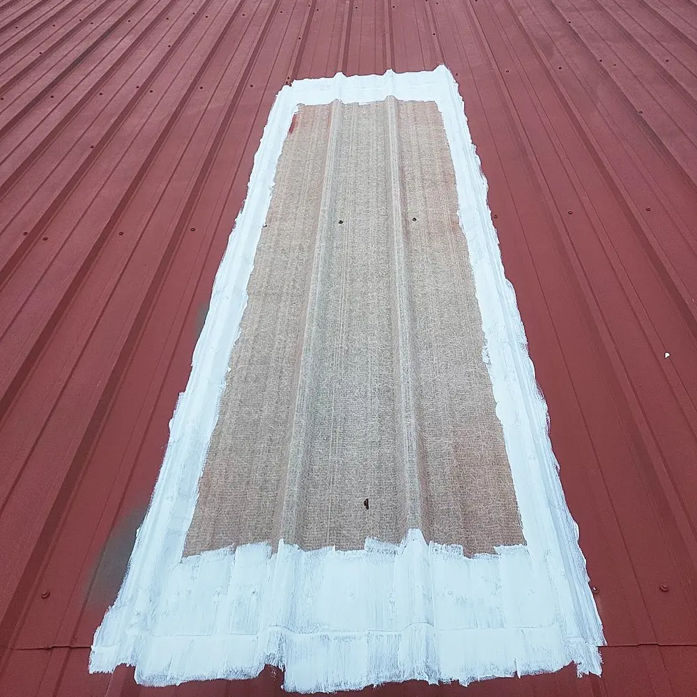 Close-up image of treated skylight with previously installed rust primer on metal roof surface.