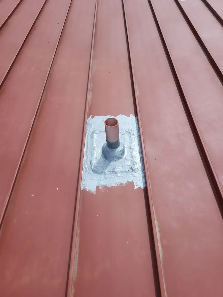 Close-up image of primer application (Red Oxide Rust Prime 912) on standing seam metal roof, showing the rust preventative aspects of the Met-A-Gard+ roof restoration system.