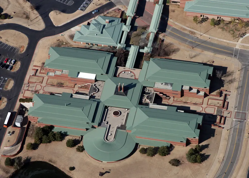 Aerial drone view of massive metal roof on university campus, showcasing the custom green-tinted High-Tensile Acrylic 211 top coat of the Met-A-Gard+ system.