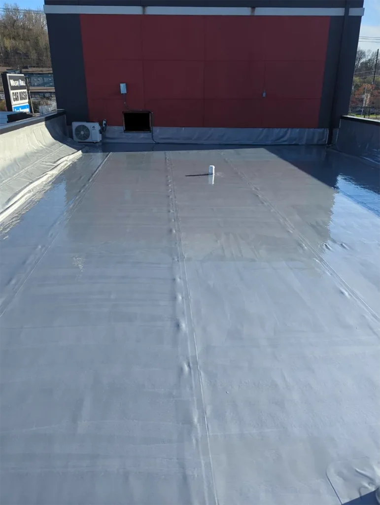 Commercial flat roof showing the urethane base coat of the Ure-A-Sil roof coating system at a car wash facility.