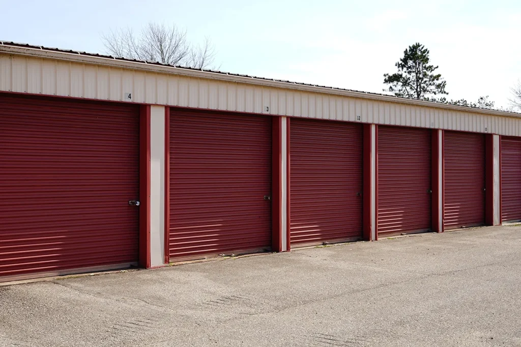 A row of red-coated roll-up doors on storage unit building