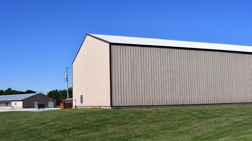 A recently coated metal building with grass and a blue sky