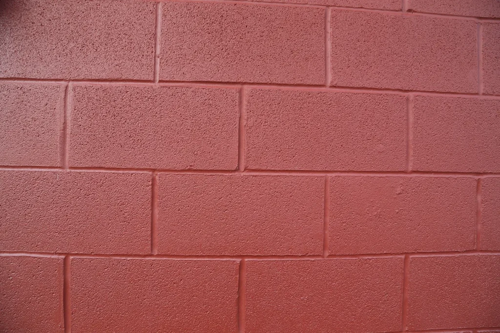 A close-up of a red-tinted coating on a brick wall