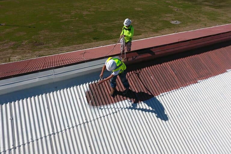 Commercial roofing contractors installing an acrylic coating system on a roof, ensuring a seamless, durable finish for enhanced protection and longevity.
