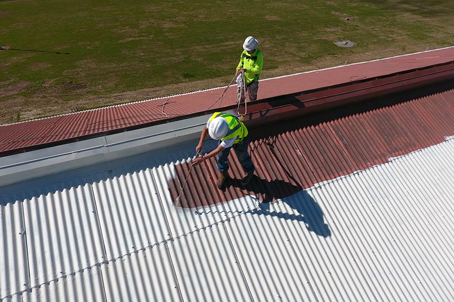 Commercial roofing contractors installing an acrylic coating system on a roof, ensuring a seamless, durable finish for enhanced protection and longevity.