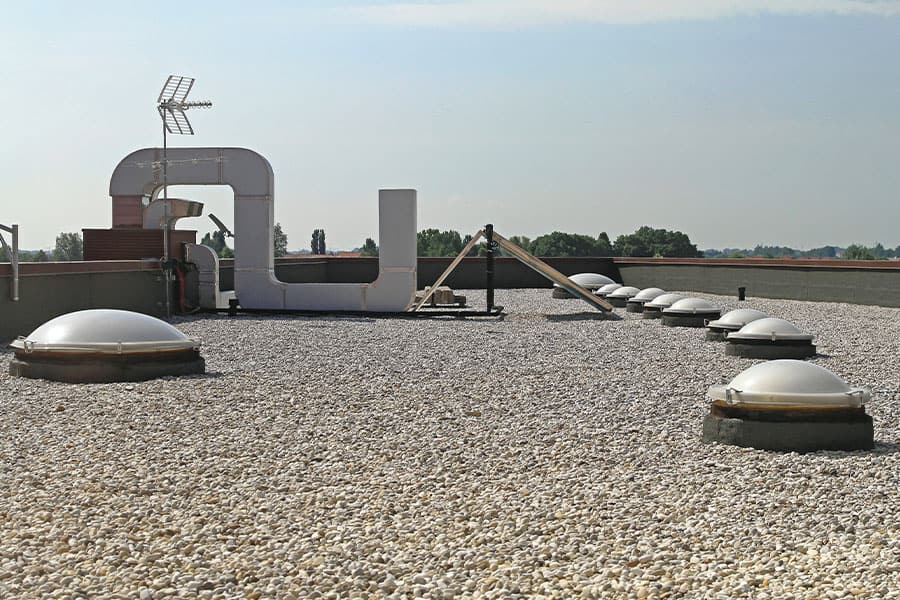 Gravel-covered BUR system on a commercial flat roof, highlighting the protective gravel layer that helps prevent UV damage and enhances the roof's resistance to the elements.