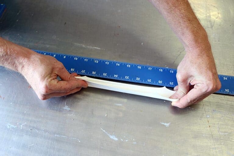 Dry butyl coating sample being tested for elongation, demonstrating its flexibility and ability to expand under stress for enhanced durability and performance.