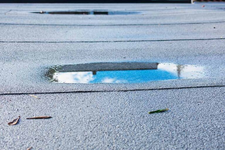 Ponding water on a modified bitumen roof, highlighting a common issue where poor drainage leads to standing water that accelerates membrane deterioration, increases the risk of leaks, and can compromise the roof's structural integrity over time if not resolved.