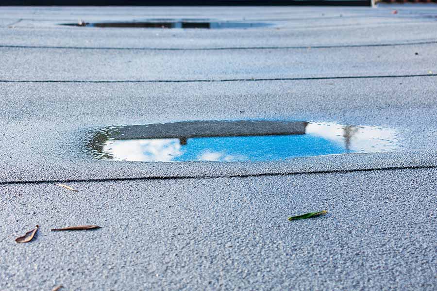 Ponding water on a modified bitumen roof, highlighting a common issue where poor drainage leads to standing water that accelerates membrane deterioration, increases the risk of leaks, and can compromise the roof's structural integrity over time if not resolved.