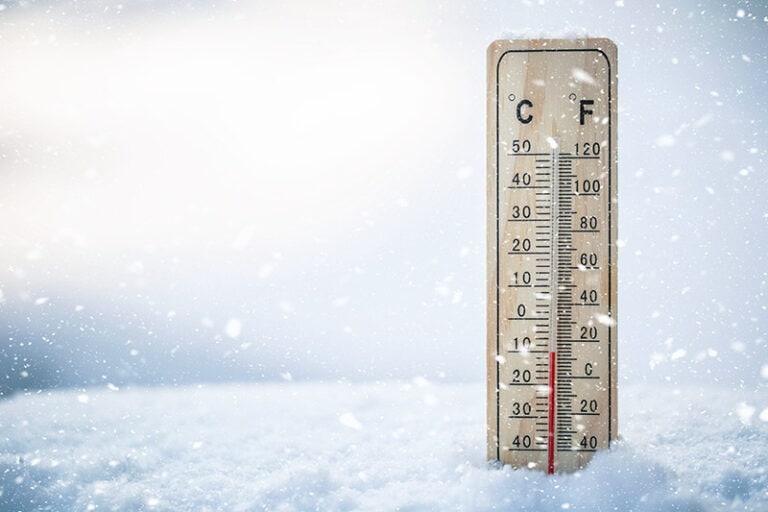 Close-up of a thermostat displaying cold temperatures, emphasizing the need for proper insulation and roofing solutions to maintain energy efficiency.
