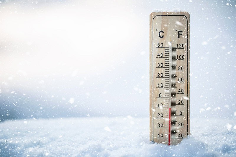 Close-up of a thermostat displaying cold temperatures, emphasizing the need for proper insulation and roofing solutions to maintain energy efficiency.