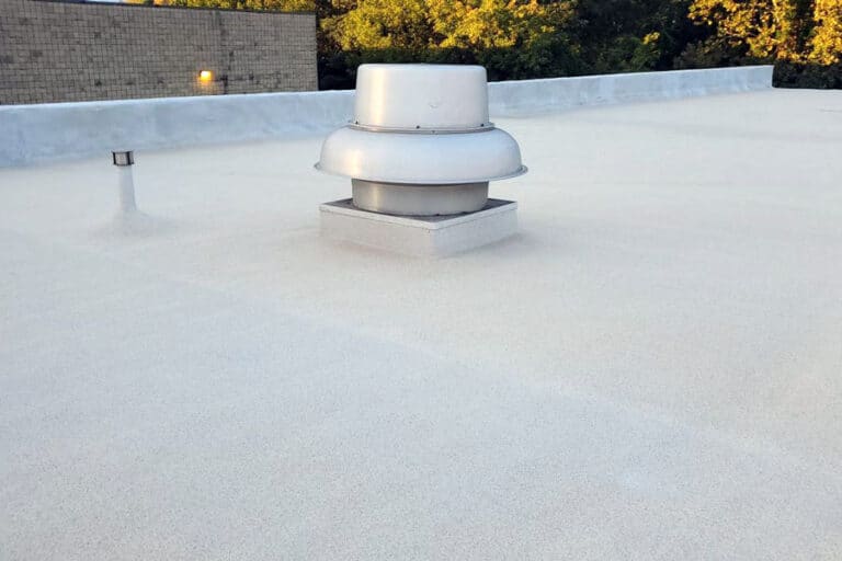 Polyurea roof coating top coat applied on a commercial flat roof, highlighting its smooth finish and enhanced durability.