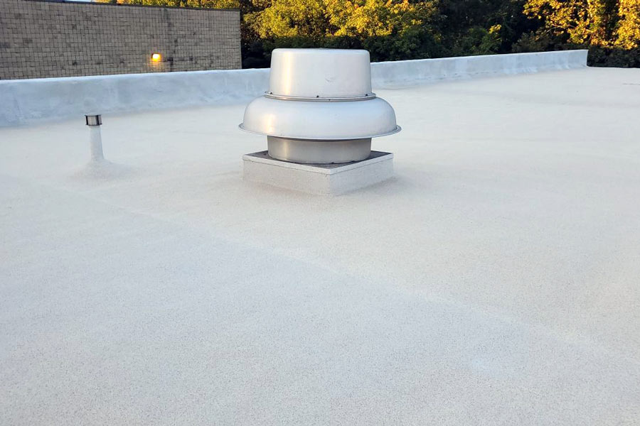 Polyurea roof coating top coat applied on a commercial flat roof, highlighting its smooth finish and enhanced durability.