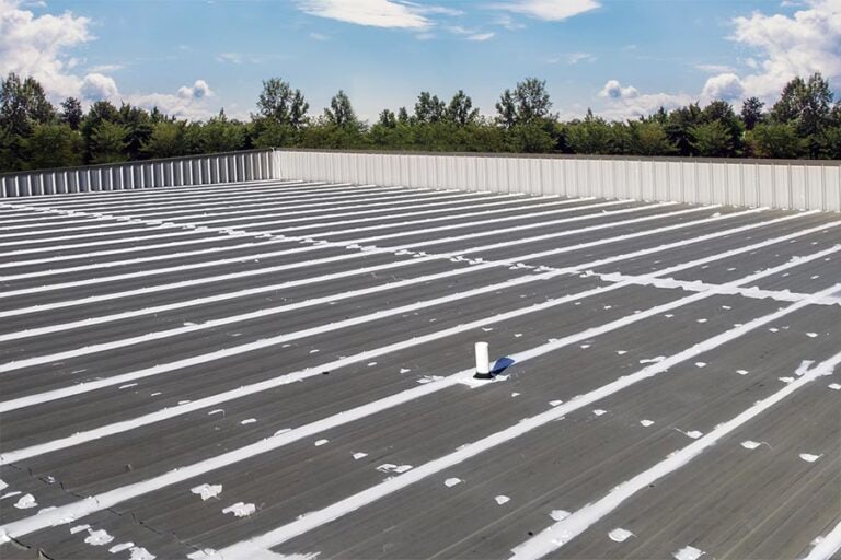 Wide view of a commercial roof with roof mastic applied to seams and details, showcasing comprehensive sealing to enhance waterproofing and protection.