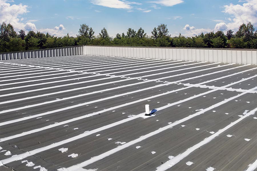 Wide view of a commercial roof with roof mastic applied to seams and details, showcasing comprehensive sealing to enhance waterproofing and protection.