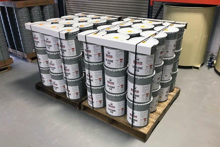 Roof coatings stored in a warehouse on pallets, showcasing organized inventory ready for application on commercial roofs.