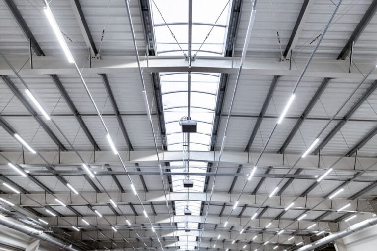 Interior view of a warehouse roof, looking up towards the ceiling, showcasing the structural elements and roofing system from below.