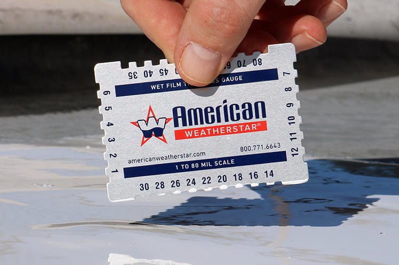 American WeatherStar branded wet mil gauge being used to check the wet mil thickness of roof coating, ensuring proper application for optimal performance and durability.