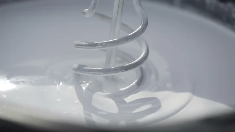 Close-up image of coating product being mixed in metal pail