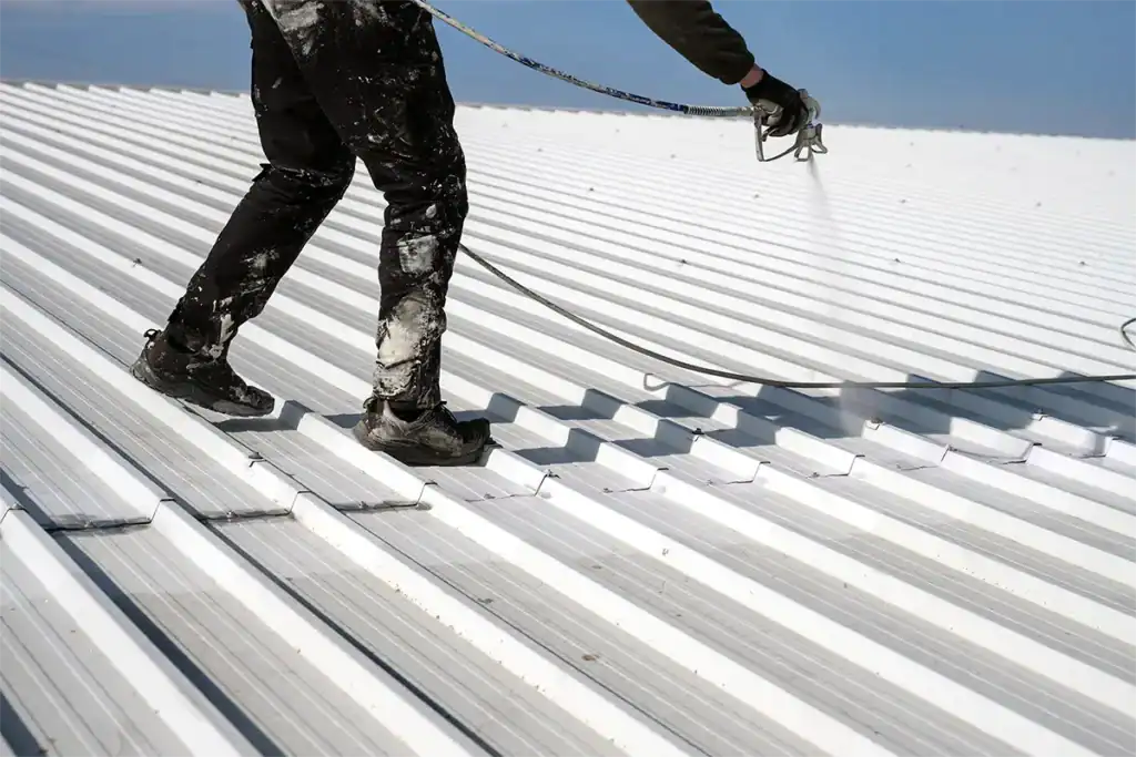 Roofing contractor spraying roof coating on metal roof