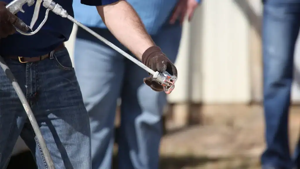 Roof coating spray gun getting pressure adjusted for demonstration.
