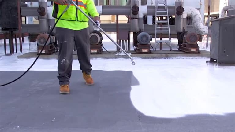 Roofer spraying silicone coatings on a flat roof
