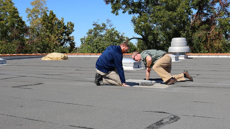 Inspecting roof with recent roof damage caused by wind.