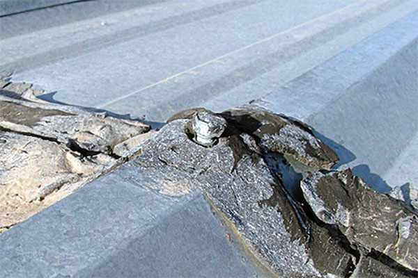 Loose fastener on metal roof overlap due to structural weakness. 