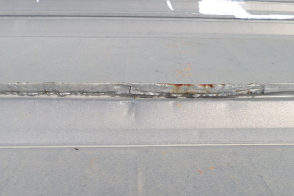 Up close image of rust seen on metal roof overlap. 